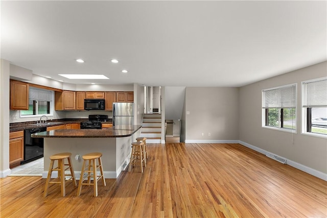 900 Tottenham Dr, Coraopolis, PA 15108 - kitchen with black appliances, a breakfast bar area, a center island, brown cabinets, and recessed lighting