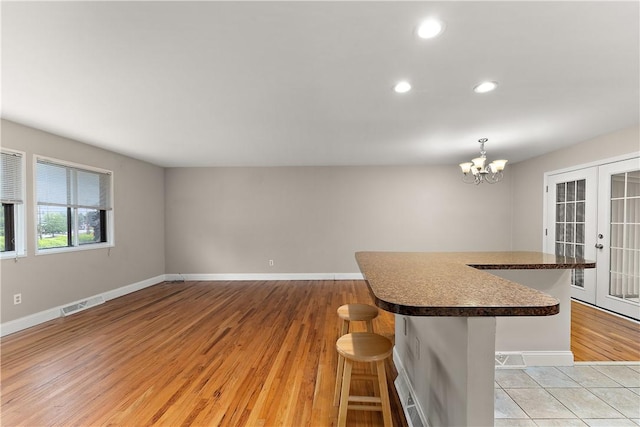 900 Tottenham Dr, Coraopolis, PA 15108 - kitchen with dark countertops, recessed lighting, a kitchen bar, light wood-type flooring, and a chandelier