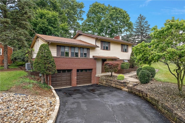 900 Tottenham Dr, Coraopolis, PA 15108 - split level home featuring asphalt driveway, a chimney, brick siding, and an attached garage