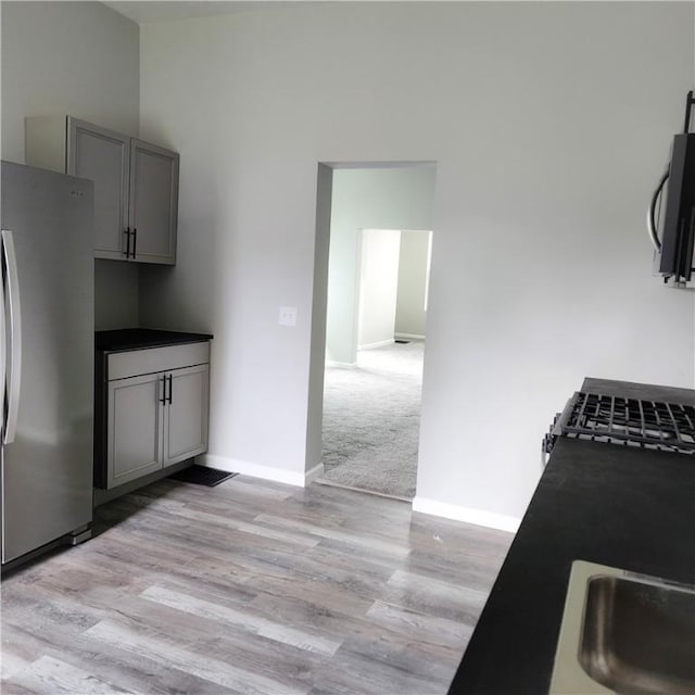 1914 Arlington Ave, Arlington, PA 15210 - kitchen featuring freestanding refrigerator, gray cabinetry, light wood finished floors, black microwave, and dark countertops