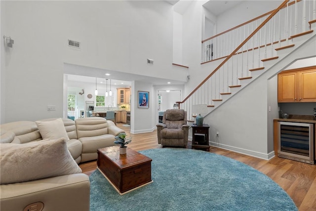 202 Providence Ct, Adams Twp, PA 16059 - living room featuring wine cooler, light wood-style flooring, stairs, a high ceiling, and bar area