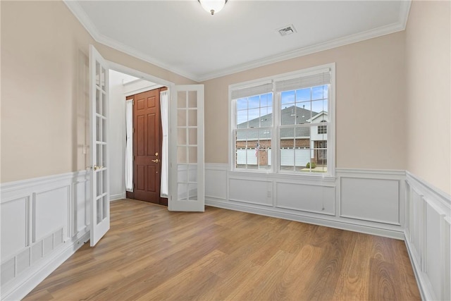 202 Providence Ct, Adams Twp, PA 16059 - empty room featuring french doors, light wood-style flooring, crown molding, a wainscoted wall, and a decorative wall