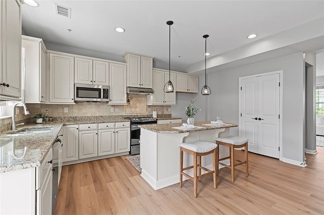 1009 Grey Fox Cir, Bridgeville, PA 15017 - kitchen featuring stainless steel appliances, light wood finished floors, a kitchen island, decorative backsplash, and recessed lighting