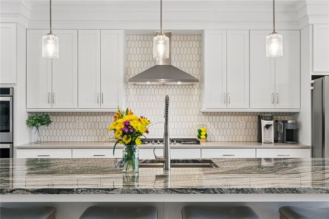349 Azalea, Peters Twp, PA 15367 - kitchen featuring a breakfast bar, wall chimney range hood, white cabinetry, decorative backsplash, and stainless steel appliances