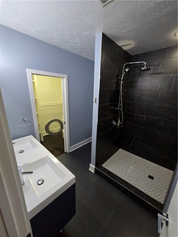 5303 Wickliff St, Lawrenceville, PA 15201 - full bath with vanity, tiled shower, a textured ceiling, and tile patterned flooring