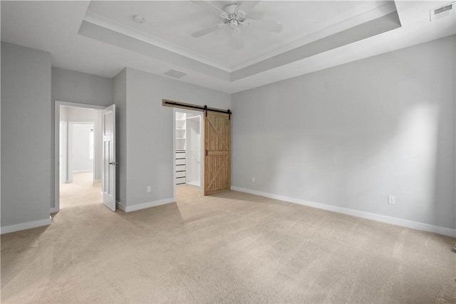 152 Cole Dr, Robinson Twp, PA 15136 - unfurnished bedroom with a tray ceiling, light colored carpet, a barn door, and a walk in closet