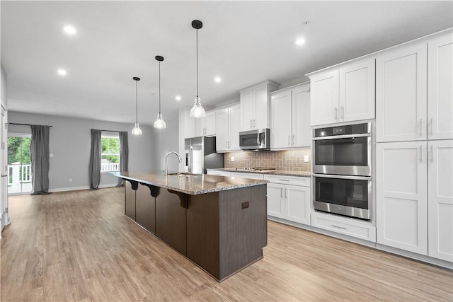 152 Cole Dr, Robinson Twp, PA 15136 - kitchen featuring appliances with stainless steel finishes, light wood-style flooring, backsplash, an island with sink, and recessed lighting