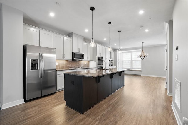 152 Cole Dr, Robinson Twp, PA 15136 - kitchen featuring appliances with stainless steel finishes, dark wood-style flooring, a kitchen island with sink, a kitchen bar, and backsplash