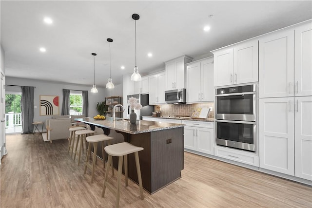 152 Cole Dr, Robinson Twp, PA 15136 - kitchen featuring stainless steel appliances, a breakfast bar area, light wood-style floors, a kitchen island with sink, and recessed lighting