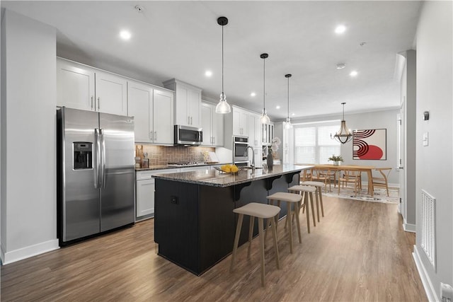 152 Cole Dr, Robinson Twp, PA 15136 - kitchen with appliances with stainless steel finishes, dark wood finished floors, a kitchen island with sink, a breakfast bar area, and recessed lighting