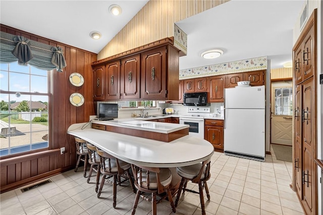 566 Ridgeview Rd, East Huntingdon, PA 15666 - kitchen featuring white appliances, light countertops, wooden walls, a peninsula, and vaulted ceiling