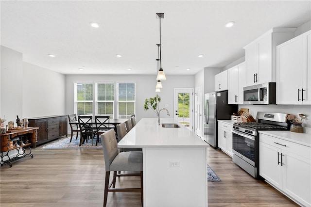 124 Rivulet Pl, Jackson Twp, PA 16063 - kitchen featuring stainless steel appliances, a center island with sink, light wood-style floors, a kitchen breakfast bar, and white cabinetry