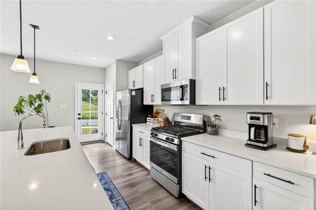 124 Rivulet Pl, Jackson Twp, PA 16063 - kitchen with appliances with stainless steel finishes, light countertops, wood finished floors, white cabinetry, and decorative light fixtures