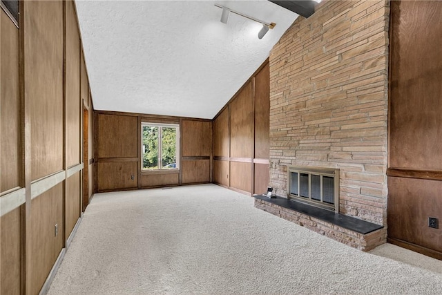 102 Barnwood Ln, Ross Twp, PA 15237 - unfurnished living room featuring vaulted ceiling, a textured ceiling, a fireplace, wooden walls, and track lighting