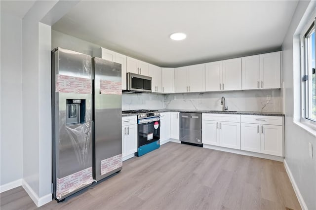 1625 Loretta Dr, Penn Hills, PA 15235 - kitchen featuring appliances with stainless steel finishes, light wood-style floors, white cabinetry, and dark stone counters