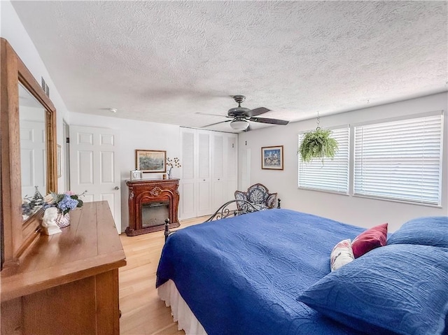 534 Hunters Path Rd, South Fayette, PA 15017 - bedroom with a textured ceiling, light wood-style floors, a fireplace, a ceiling fan, and a closet