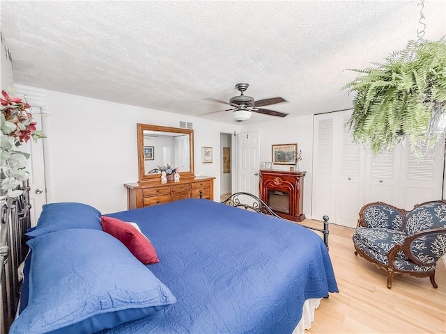 534 Hunters Path Rd, South Fayette, PA 15017 - bedroom with light wood-style floors, a textured ceiling, a closet, ceiling fan, and a fireplace