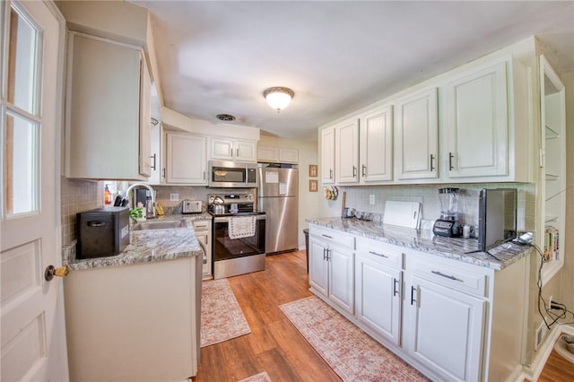 5215 Caste Dr, Whitehall, PA 15236 - kitchen with stainless steel appliances, light wood-style floors, white cabinets, and backsplash