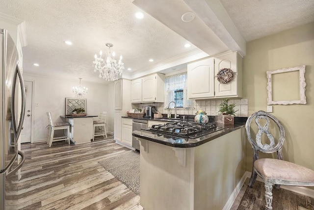 1115 Valleyview Dr, Cecil, PA 15055 - kitchen featuring stainless steel appliances, a textured ceiling, a chandelier, dark countertops, and a kitchen breakfast bar