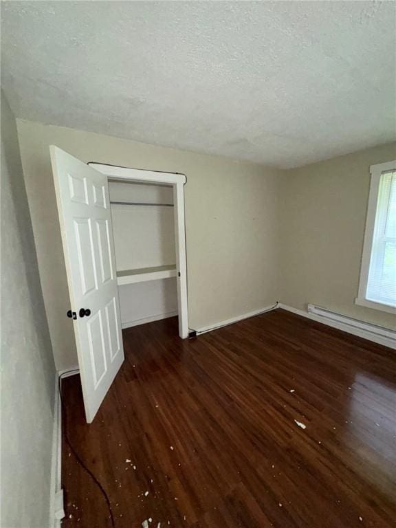 5015 Walnut St, Versailles Boro, PA 15132 - unfurnished bedroom with hardwood / wood-style flooring, a textured ceiling, a closet, and a baseboard heating unit