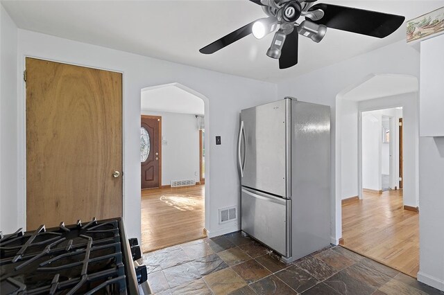 242 Millport Rd, West Mifflin, PA 15122 - kitchen featuring freestanding refrigerator, arched walkways, ceiling fan, stone tile flooring, and gas range oven