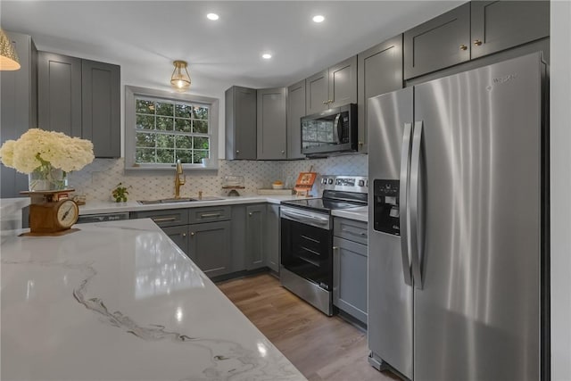 231 W Shaffer Rd, Center Twp, PA 15001 - kitchen featuring stainless steel appliances, light wood-style flooring, light stone countertops, gray cabinetry, and decorative backsplash