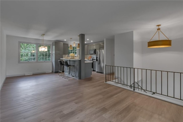231 W Shaffer Rd, Center Twp, PA 15001 - kitchen with gray cabinets, appliances with stainless steel finishes, a breakfast bar area, light wood finished floors, and light countertops