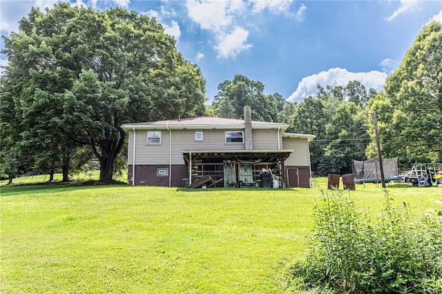 132 Spaugy Hollow Rd, Bullskin Twp, PA 15425 - rear view of property featuring a trampoline, a lawn, and a chimney