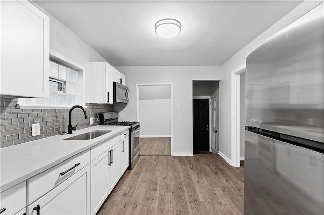 613-615 W Main St, Carnegie, PA 15106 - kitchen featuring stainless steel appliances, tasteful backsplash, light countertops, white cabinetry, and light wood-style floors