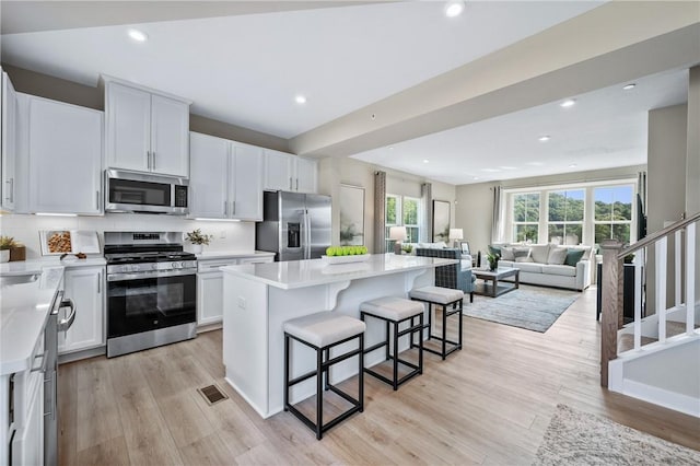 214 Hunter Dr, Moon/Crescent Twp, PA 15108 - kitchen with appliances with stainless steel finishes, a kitchen island, open floor plan, a kitchen bar, and light wood-type flooring