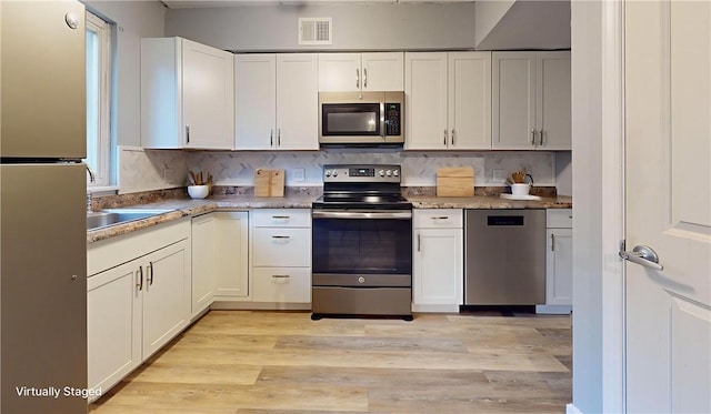 120 Rivermont Ct, Harmar, PA 15024 - kitchen featuring stainless steel appliances, light wood-style flooring, decorative backsplash, and white cabinets