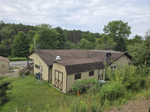 2879 Winslow Hill Rd, Benezette, PA 15821 - view of side of home with roof with shingles, a storage shed, a yard, and a view of trees