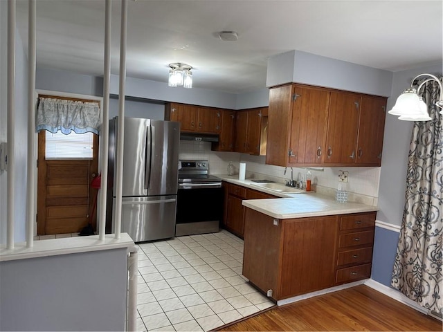 118 Manchester Dr, Hempfield Twp, PA 15642 - kitchen featuring stainless steel appliances, a peninsula, under cabinet range hood, tasteful backsplash, and light countertops