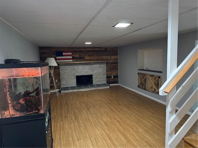 118 Manchester Dr, Hempfield Twp, PA 15642 - unfurnished living room featuring stairs, wood finished floors, a fireplace with raised hearth, and wooden walls