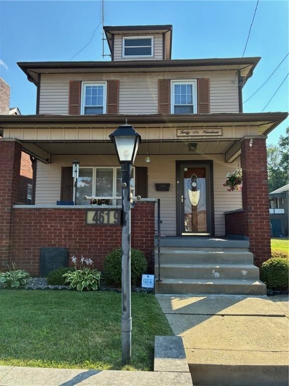4619 5th Ave, Beaver Falls, PA 15010 - american foursquare style home with covered porch, a front lawn, and brick siding