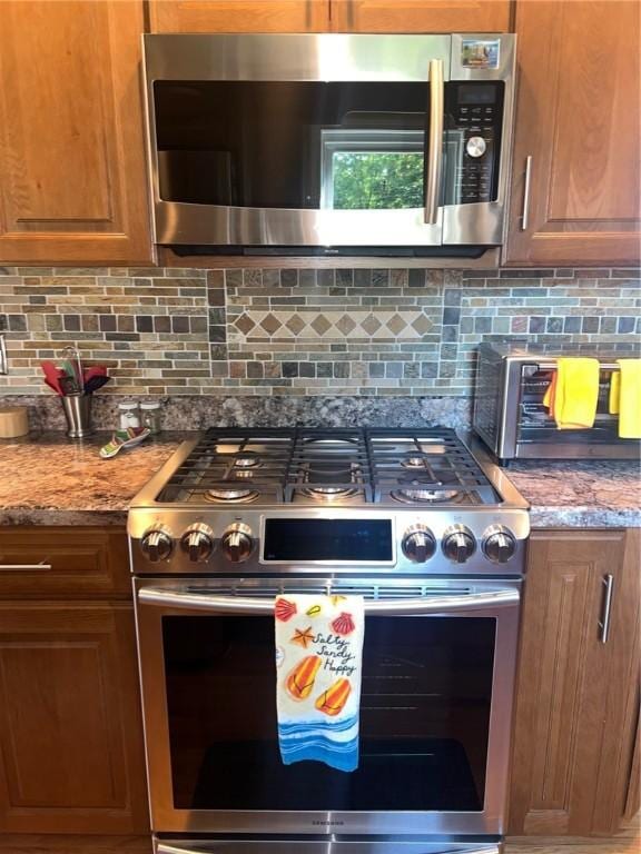 4619 5th Ave, Beaver Falls, PA 15010 - kitchen featuring stainless steel appliances, backsplash, brown cabinetry, and light stone countertops