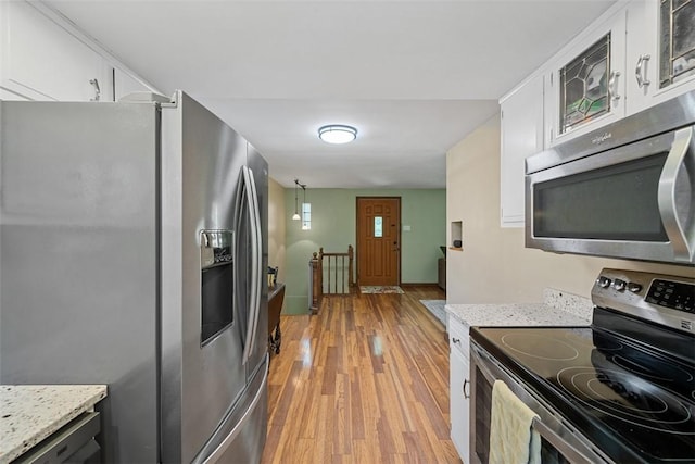 723 Rose Ln, Baldwin Twp, PA 15234 - kitchen with appliances with stainless steel finishes, light wood-style floors, white cabinets, glass insert cabinets, and light stone counters