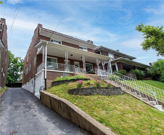 5553 Pocusset St, Squirrel Hill, PA 15217 - view of front of property featuring brick siding, covered porch, and a front lawn