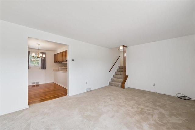 409 Westland Dr, Hempfield Twp, PA 15601 - unfurnished living room with carpet flooring, stairway, and a chandelier
