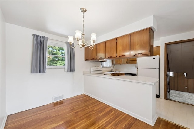 409 Westland Dr, Hempfield Twp, PA 15601 - kitchen featuring freestanding refrigerator, range with electric stovetop, wood finished floors, brown cabinets, and light countertops