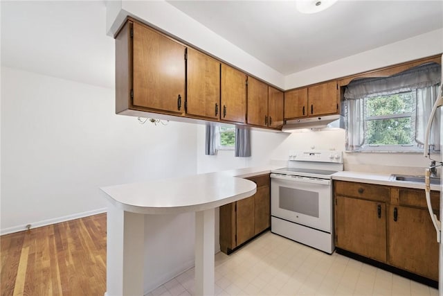 409 Westland Dr, Hempfield Twp, PA 15601 - kitchen featuring electric stove, under cabinet range hood, a peninsula, and light countertops
