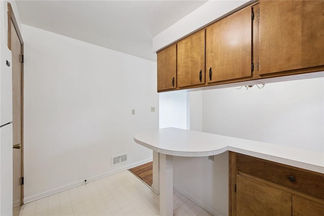 409 Westland Dr, Hempfield Twp, PA 15601 - kitchen featuring light countertops, brown cabinetry, light floors, and a peninsula