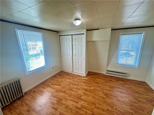 1023 Burtner Rd, Harrison Twp, PA 15065 - unfurnished bedroom featuring radiator heating unit, baseboard heating, light wood finished floors, and multiple windows