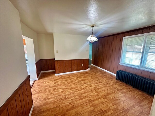 1023 Burtner Rd, Harrison Twp, PA 15065 - spare room featuring light wood finished floors, radiator heating unit, wood walls, and a wainscoted wall