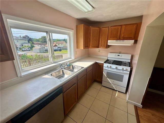 1023 Burtner Rd, Harrison Twp, PA 15065 - kitchen with gas range gas stove, stainless steel dishwasher, under cabinet range hood, light countertops, and brown cabinetry