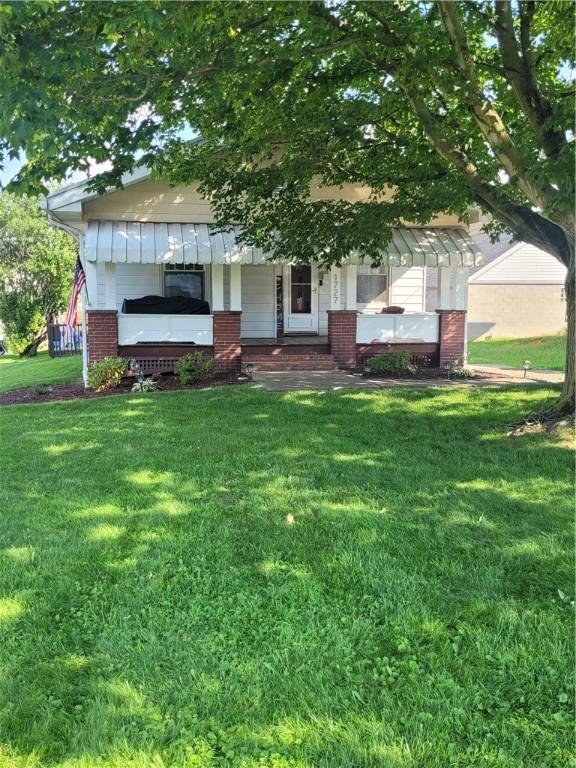 1727 Tyler St, Aliquippa, PA 15001 - view of property hidden behind natural elements featuring brick siding, a front lawn, and a porch