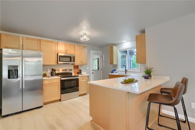 1611 18th Ave, Patterson Heights, PA 15010 - kitchen featuring appliances with stainless steel finishes, light brown cabinets, a peninsula, light countertops, and light wood-style flooring