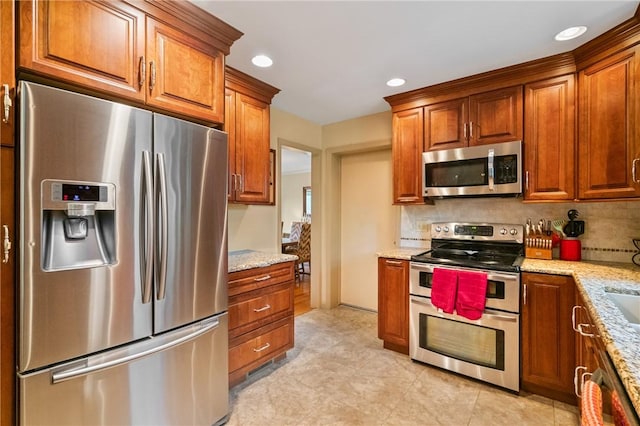 1026 Cambridge St, Harrison Twp, PA 15065 - kitchen with appliances with stainless steel finishes, light stone counters, brown cabinets, recessed lighting, and tasteful backsplash
