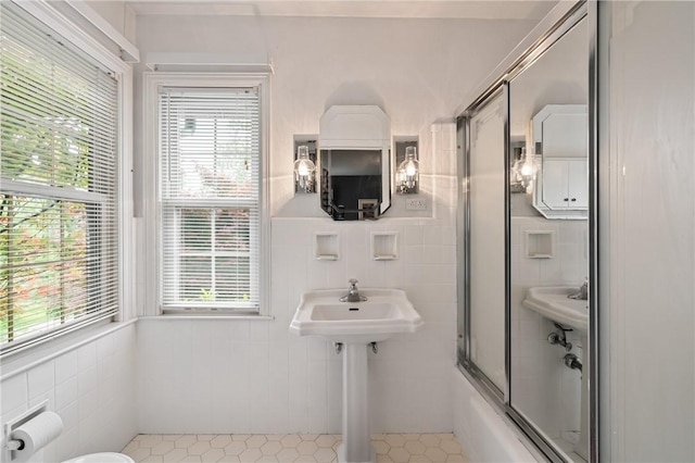 1026 Cambridge St, Harrison Twp, PA 15065 - bathroom featuring tile walls, plenty of natural light, tile patterned floors, bath / shower combo with glass door, and a wainscoted wall