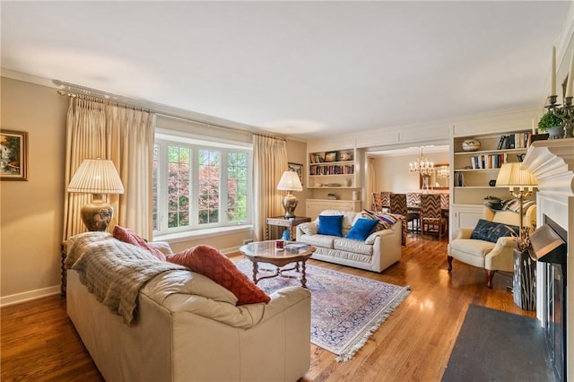 1026 Cambridge St, Harrison Twp, PA 15065 - living area featuring wood finished floors, a fireplace with flush hearth, a chandelier, crown molding, and built in features